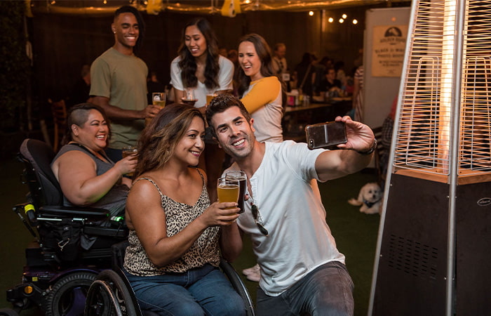 A woman in a wheelchair happily takes a selfie with a group of friends presenting trust relationship